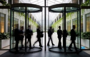 A blurred group of professional individuals in suits exiting a revolving door