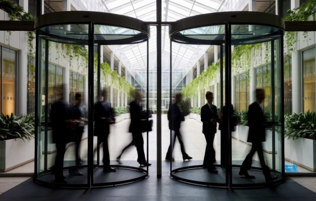 A blurred group of professional individuals in suits exiting a revolving door