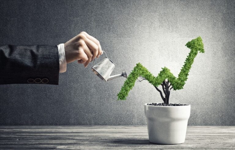 Hand watering a tree in the shape of an arrow pointing up