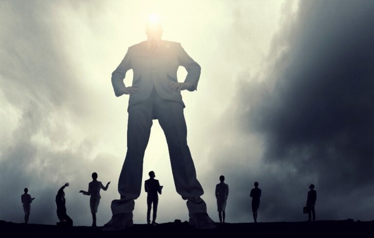 Giant person in business suit standing over smaller business people at his feet