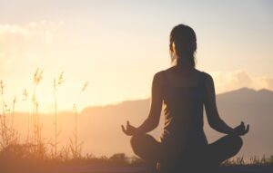 silhouette practicing yoga on mountain