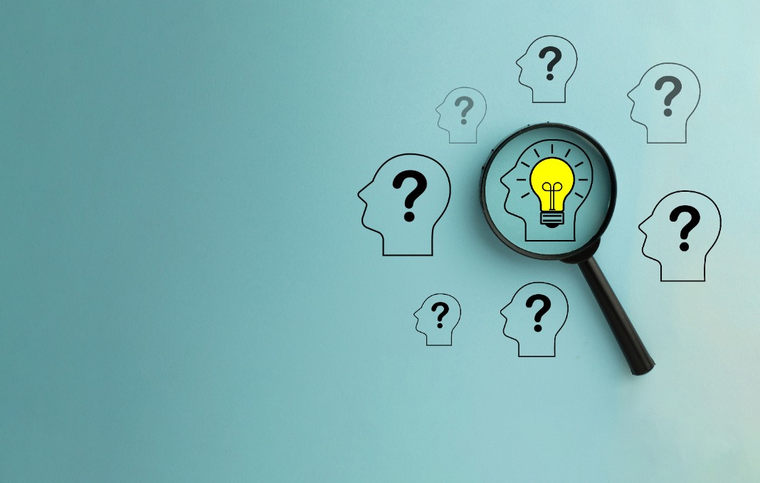 Magnify focus on Head with glowing light bulb icon among Head with Question mark icon over blue background